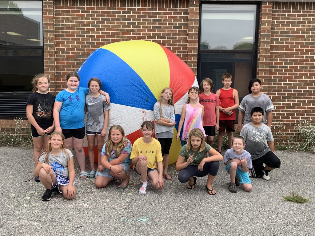 Students  standing by a huge beach ball outisde the school 