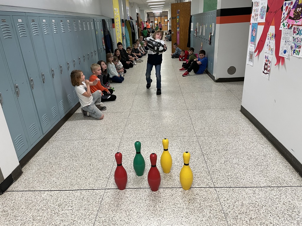 Students lined up by lockers watching a student Turkey Bowling.
