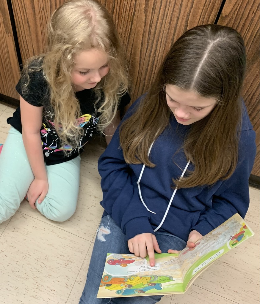 Two students side by side reading to each other 