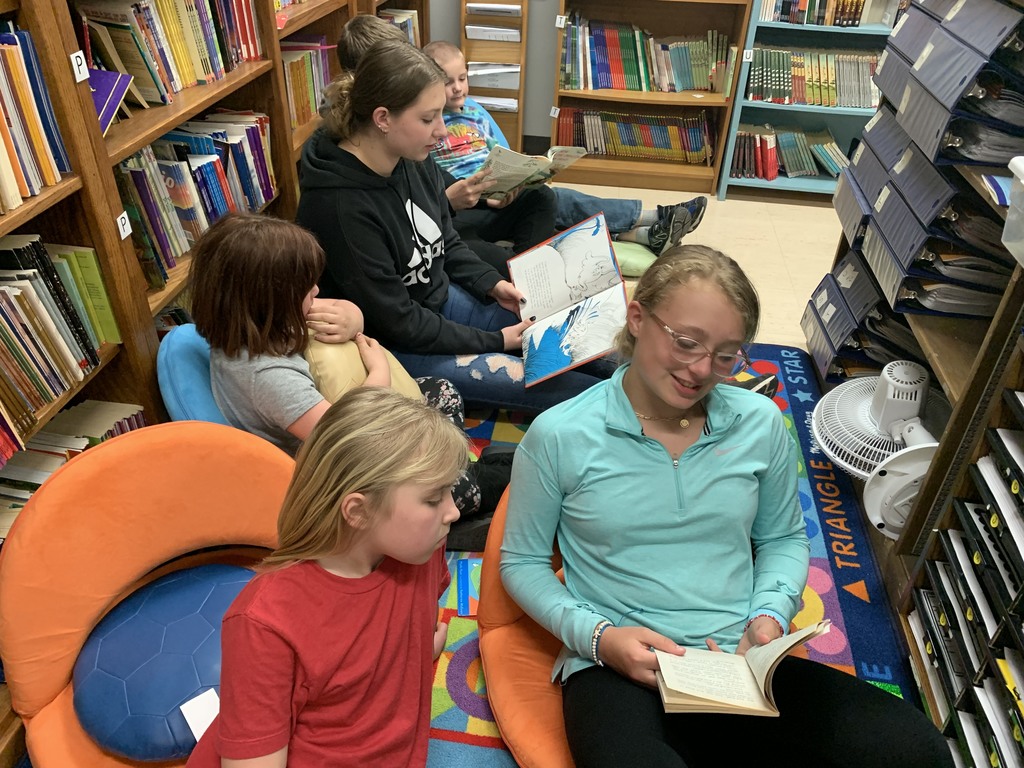 picture of a group of older students reading to the younger students after school in a cluv