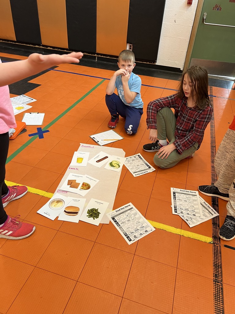 Students in gym racing to find food cards to make a well balanced meal with the correct portion sizes.